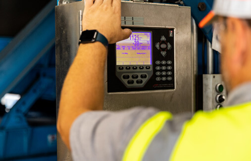 An LTR employee checking over console information on a tire processing machine