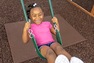 A girl swinging over rubber playground mulch