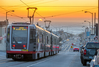 Electrical trams moving through a city at sunset