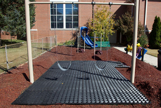 A playground with an Access-a-Mat installed beneath swings