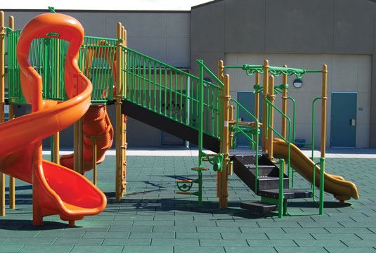 Green Kid Kushion mats installed around a jungle gym