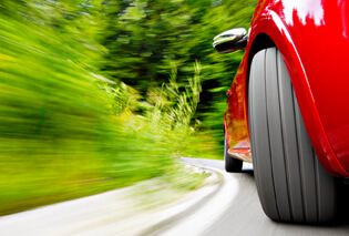 A close up of a red sports car's tire zooming across a road