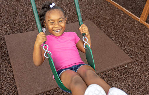 A girl swinging over rubber playground mulch