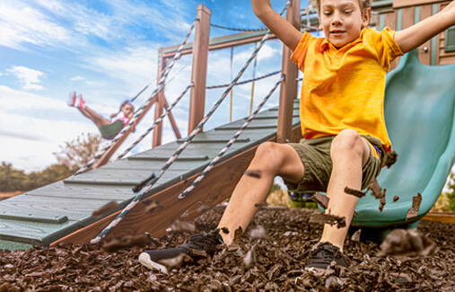 A boy sliding into rubber nugget mulch