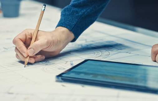 LTR employee sketching blueprints while looking at a tablet