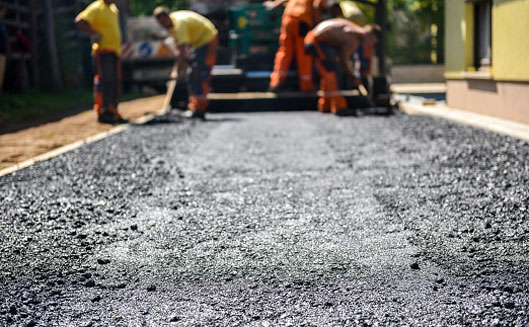 Construction workers laying out asphalt